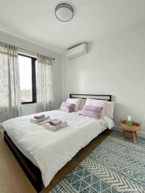 bedroom with a wall unit AC and wood-type flooring