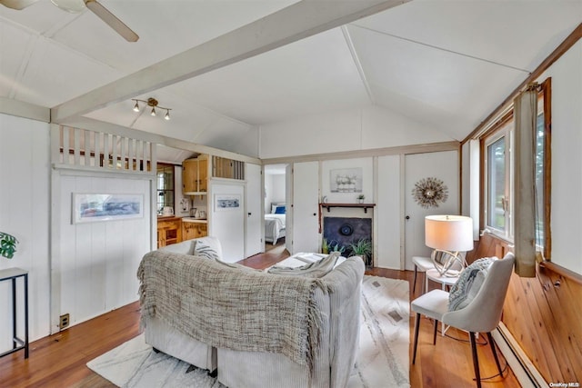 living room featuring vaulted ceiling, ceiling fan, a baseboard heating unit, light hardwood / wood-style flooring, and wood walls