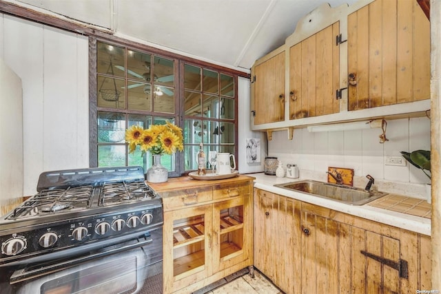 kitchen featuring gas stove, ceiling fan, lofted ceiling, and sink