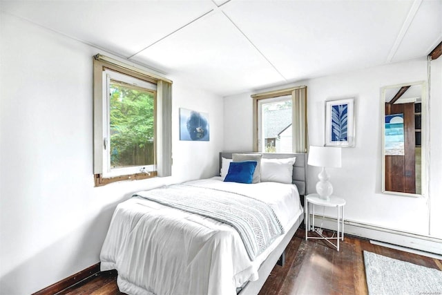 bedroom with baseboard heating and dark wood-type flooring