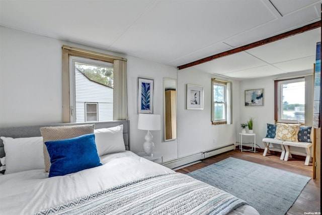 bedroom with multiple windows, dark wood-type flooring, and a baseboard radiator