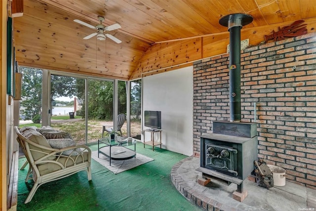 sunroom / solarium featuring a wood stove, ceiling fan, wooden ceiling, and lofted ceiling