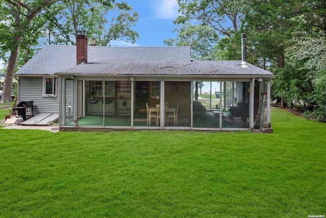 rear view of property with a lawn and a sunroom