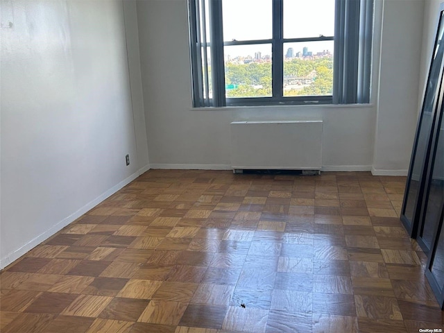 empty room featuring radiator heating unit and dark parquet floors