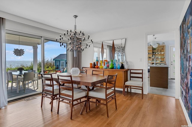 dining space with sink, a notable chandelier, and light hardwood / wood-style floors