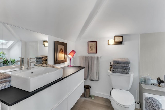 bathroom featuring vanity, lofted ceiling with skylight, and toilet