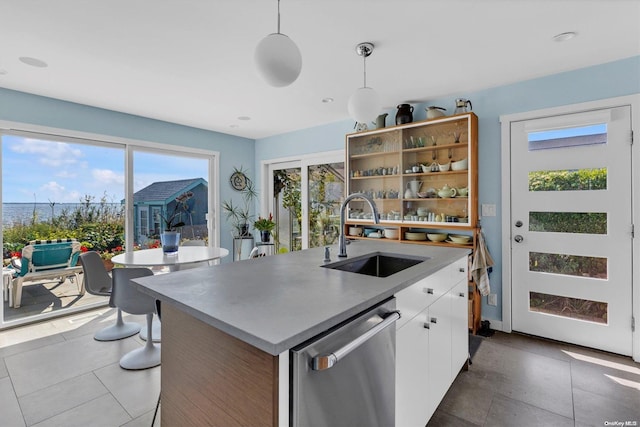 kitchen featuring sink, stainless steel dishwasher, an island with sink, pendant lighting, and white cabinets