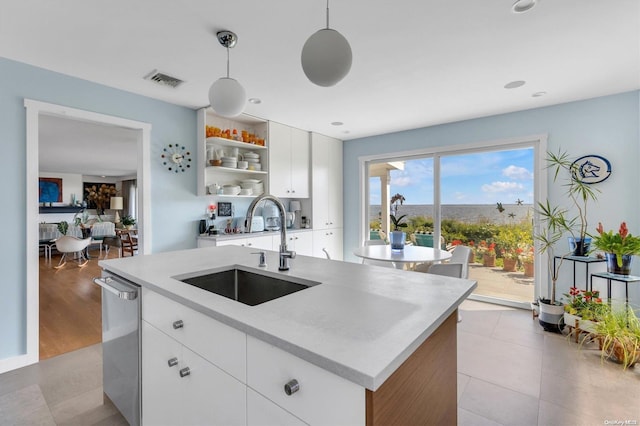 kitchen with sink, hanging light fixtures, dishwasher, an island with sink, and white cabinets