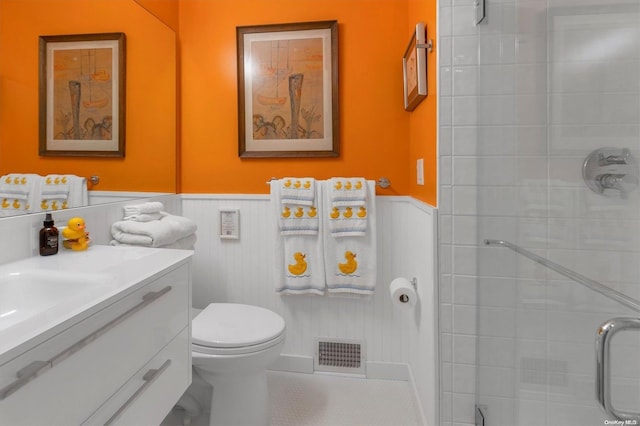 bathroom featuring vanity, a shower with door, and toilet