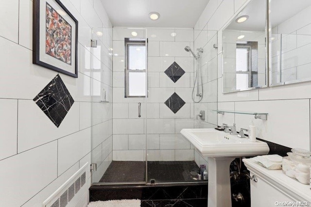 bathroom featuring toilet, a shower with door, and tile walls