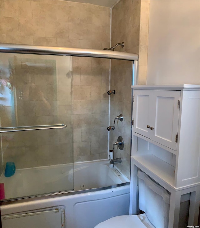 bathroom featuring toilet and combined bath / shower with glass door