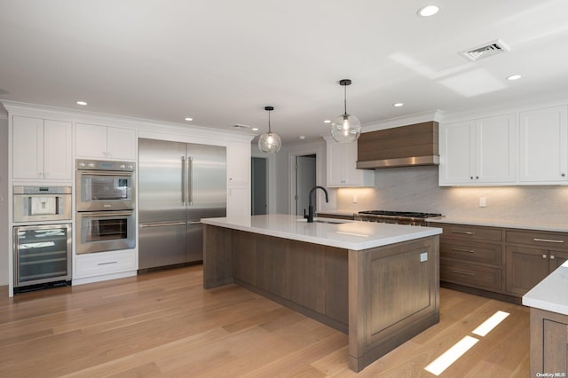 kitchen featuring white cabinetry, sink, wall chimney exhaust hood, wine cooler, and appliances with stainless steel finishes