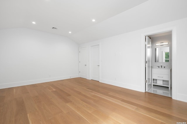 spare room with light hardwood / wood-style flooring, lofted ceiling, and sink