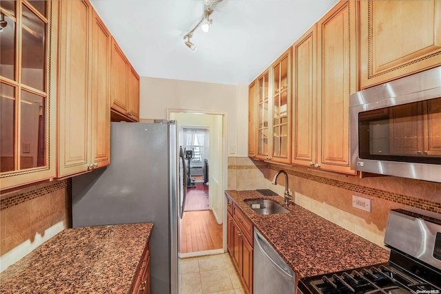 61-15 97th St Unit 5A, Rego Park, NY 11374 - kitchen with a sink, stainless steel appliances, dark stone counters, glass insert cabinets, and decorative backsplash