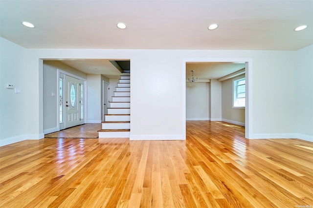 unfurnished living room with an inviting chandelier and light wood-type flooring