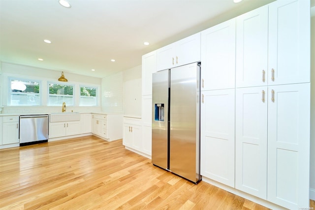 kitchen with white cabinets, sink, stainless steel appliances, and light hardwood / wood-style flooring