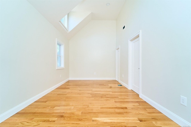 additional living space with light hardwood / wood-style flooring and high vaulted ceiling