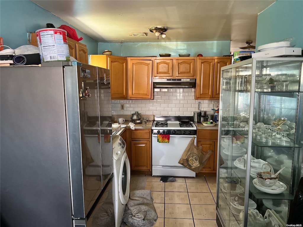 kitchen featuring washer / clothes dryer, stainless steel fridge, fridge, white range with gas cooktop, and decorative backsplash