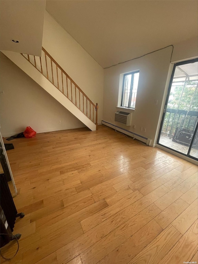 interior space featuring light wood-type flooring, a wall unit AC, and a baseboard heating unit