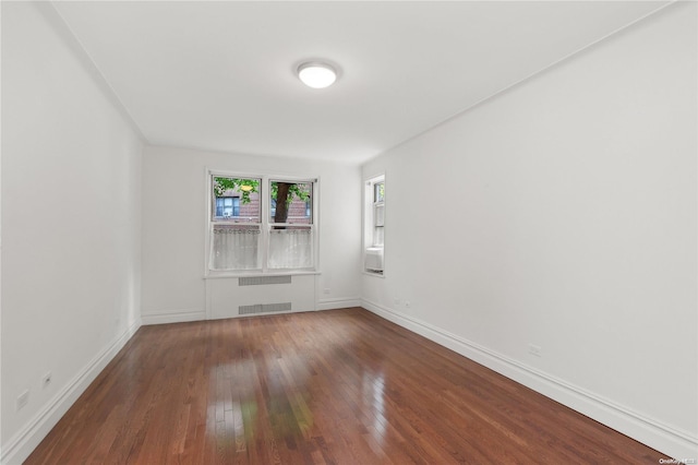 empty room with hardwood / wood-style flooring and radiator heating unit