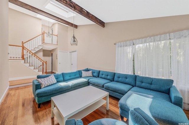 living room with hardwood / wood-style floors, beam ceiling, high vaulted ceiling, and a skylight