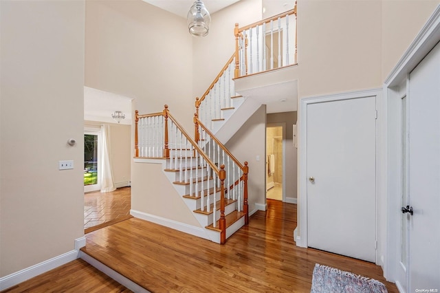 stairway featuring wood-type flooring and a towering ceiling