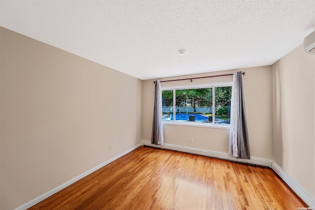 empty room with a textured ceiling and light hardwood / wood-style floors