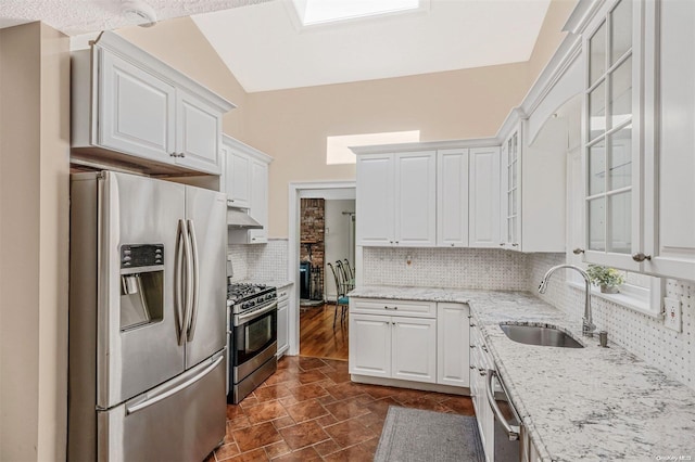 kitchen featuring vaulted ceiling, stainless steel appliances, and white cabinetry