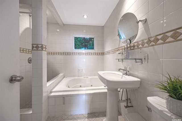 bathroom with tiled bath, tile walls, and toilet