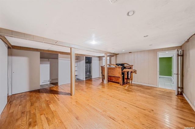 basement featuring wood walls and light hardwood / wood-style floors