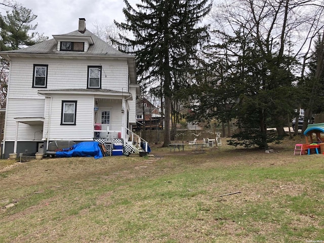 back of house featuring covered porch and a lawn