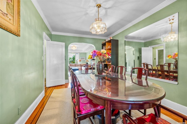 dining room with a chandelier, light wood-type flooring, and crown molding