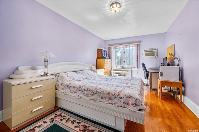 bedroom featuring light hardwood / wood-style floors and a wall unit AC