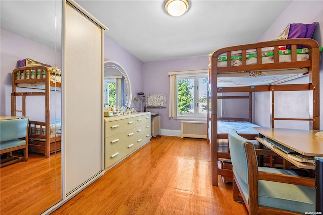 bedroom with radiator heating unit and light hardwood / wood-style floors