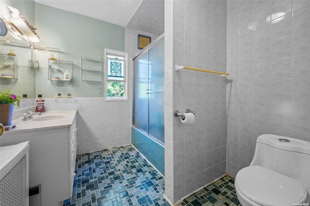 full bathroom with tile patterned floors, vanity, shower / bath combination with glass door, tile walls, and toilet