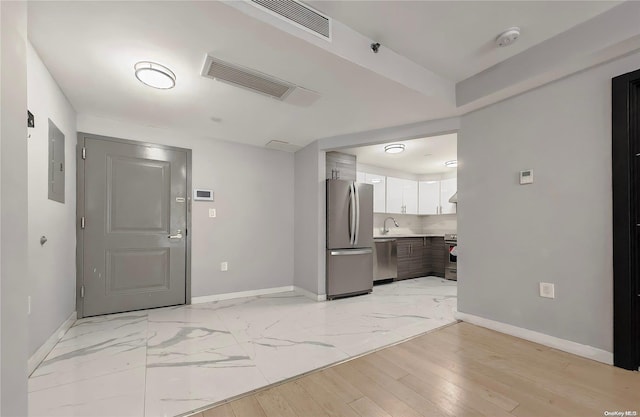 foyer with light wood-type flooring, sink, and electric panel