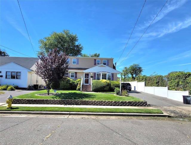 view of front of property with a front yard and central AC unit