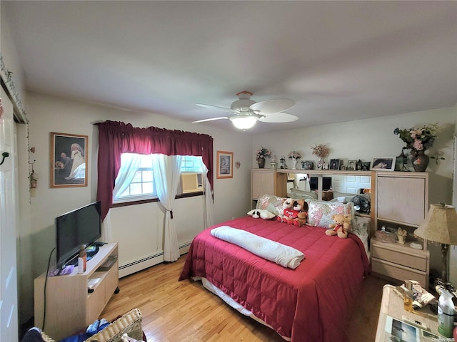 bedroom featuring ceiling fan, light wood-type flooring, and a baseboard heating unit