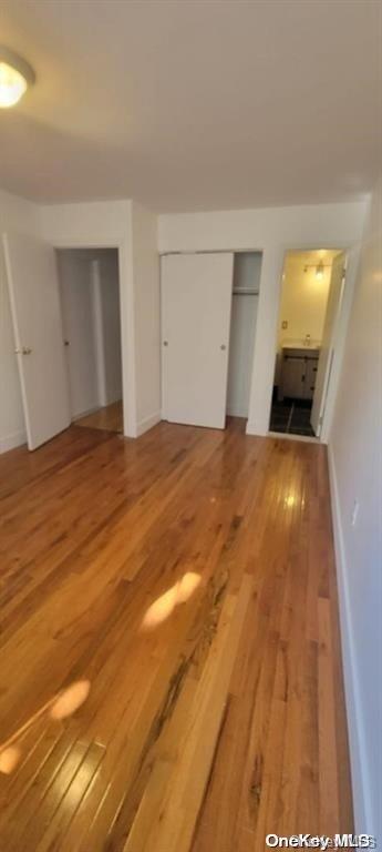 unfurnished bedroom with hardwood / wood-style flooring and two closets