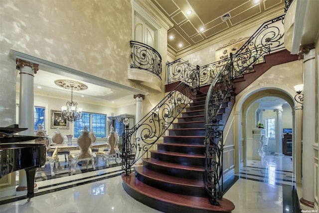 stairs with decorative columns, a healthy amount of sunlight, a high ceiling, and a notable chandelier