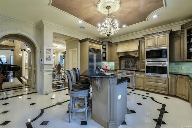 kitchen with decorative backsplash, premium range hood, pendant lighting, built in appliances, and an island with sink