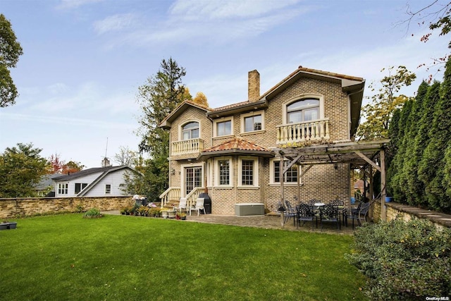 back of property featuring a balcony and a lawn