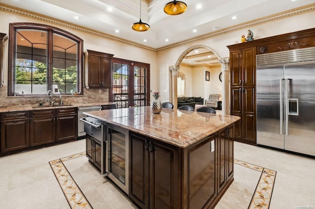 kitchen with pendant lighting, a center island, built in refrigerator, ornamental molding, and tasteful backsplash