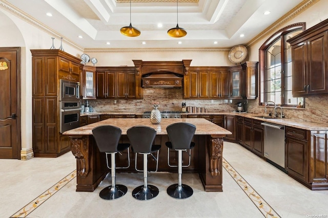 kitchen with decorative light fixtures, a kitchen island, appliances with stainless steel finishes, and a tray ceiling