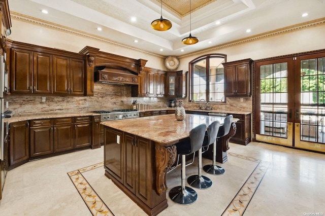 kitchen featuring a center island, sink, backsplash, crown molding, and decorative light fixtures