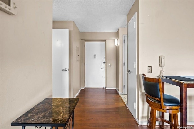 hall with a textured ceiling and dark wood-type flooring