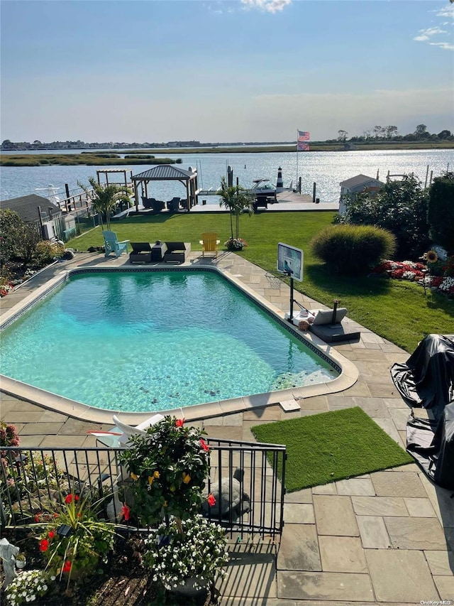 view of pool featuring a lawn, a water view, and a patio