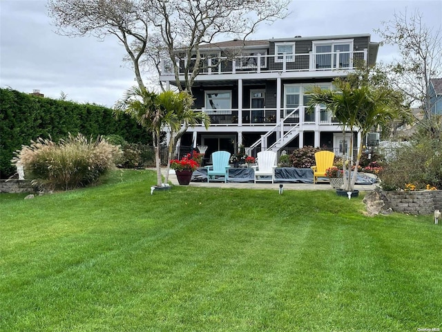 back of property featuring a yard, a balcony, and a patio area