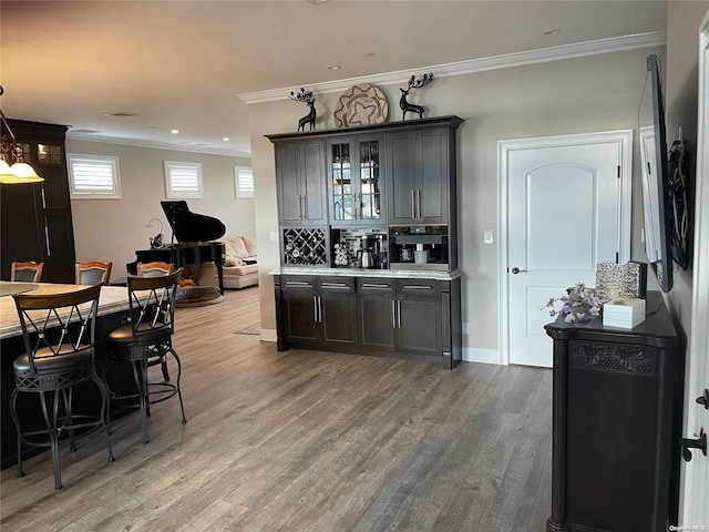 bar with light wood-type flooring, backsplash, dark brown cabinets, crown molding, and pendant lighting