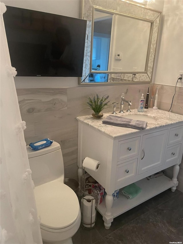 bathroom with tasteful backsplash, tile patterned floors, toilet, vanity, and tile walls